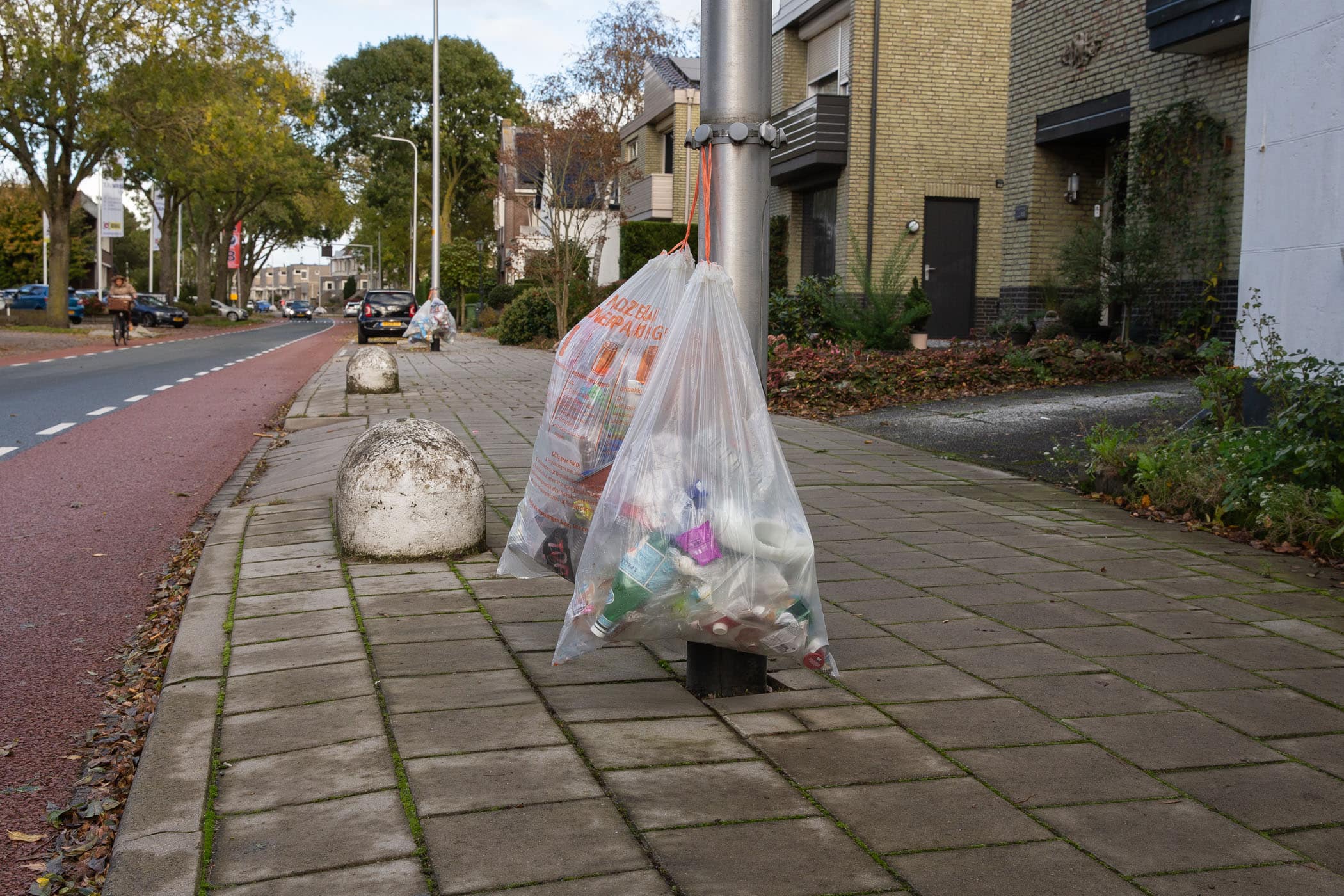 plastic zakken met pmd-afval hangen aan een lantarenpaal om opgehaald te worden