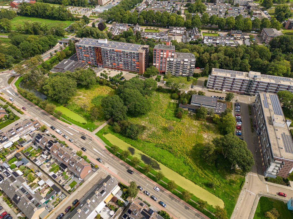 Luchtfoto met groen gras en bomen bij de appartementen Anne frankcentrum aan de ene kant en de Chopinlaan aan de andere kant. Er ligt een weg tussen die uitkomt op de Beethoven en Kerkweg-West