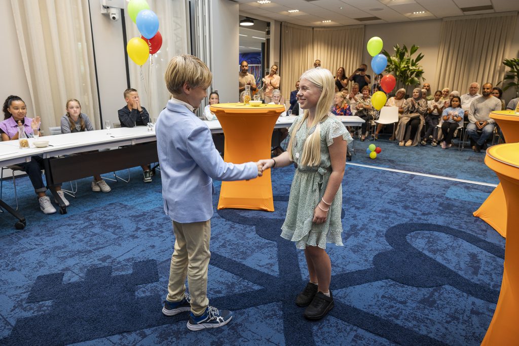 Jongen feliciteert meisje in raadzaal gemeentehuis Waddinxveen