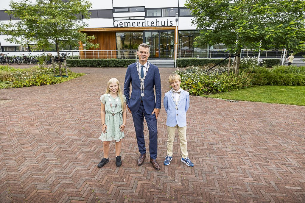 Burgemeester Nieuwenhuis met kinderburgermeesters Mathijs en Kiki voor het gemeentehuis